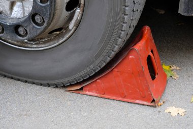 Bir arabanın direksiyonunun altında kırmızı tekerlek tıkanmış. Araba tamiri. Makine onarımı için metal raf.