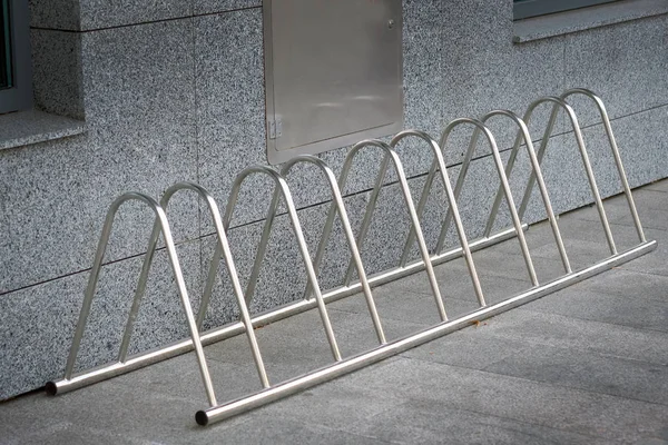 Metal parking for bicycles. Bicycle parking with sections for five places. Parking on gray tiled floor. Reliable protection of the bicycle against theft.