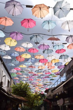 Çok renkli şemsiyeler güneşten korunmak için caddeler arasında asılı duruyor. Türkiye, Antalya.