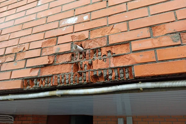 Kırmızı cephe tuğlası çatladı ve su tarafından tahrip edildi. Klimadan bir boru ve bir apartmanın duvarına tuğla parçaları yerleştirilmiş..