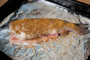 Kuru otlar ve baharatlarla süslenmiş balık filetosu. Pişirme tepsisinde çiğ balık. Evde fırında balık pişirmek..