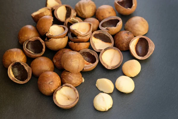 Macadamia nut shell on black background. Raw macadamia nuts and brown shells.