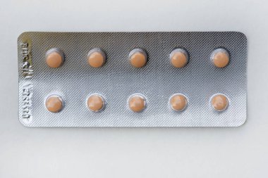 Beyaz arka planda haplarla su toplamış. Paket başına küçük kahverengi haplar. Tıbbi tedavi, randevu.