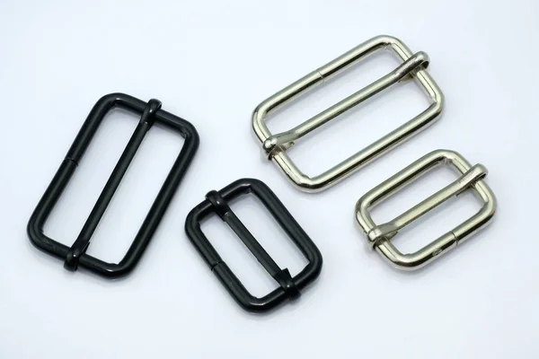Metal fittings for changing the length of the belt. Padding for a strap of bags and backpacks on a white background. Black and chrome-plated banner fittings for making accessories.