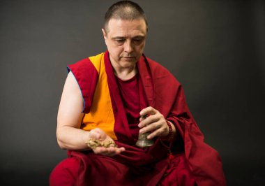 Keşiş ayin çanı ve vajra tutuyor.