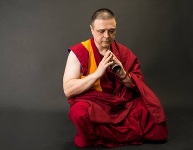 Keşiş ayin çanı ve vajra tutuyor.