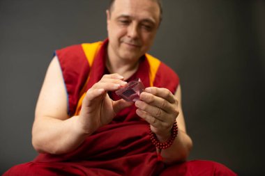 Kırmızılı Budist keşiş elinde cam bir kristal tutuyordu.