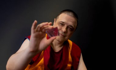 Kırmızılı Budist keşiş elinde cam bir kristal tutuyordu.