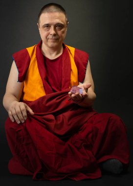 Kırmızılı Budist keşiş elinde cam bir kristal tutuyordu.