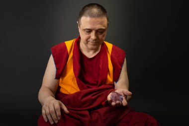 Kırmızılı Budist keşiş elinde cam bir kristal tutuyordu.