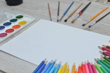 Çizim aletleri, kırtasiye malzemeleri, sanatçının çalışma yeri. Boya ve kalemler ve boş kağıtlar ahşap masa, üst görüş, düz döşeme, kopyalama alanı. okul çizim malzemeleri