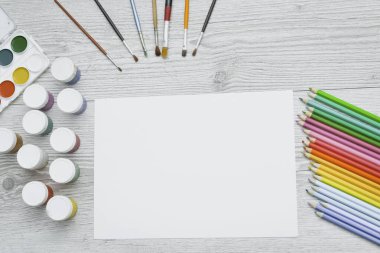 Çizim aletleri, kırtasiye malzemeleri, sanatçının çalışma yeri. Boya ve kalemler ve boş kağıtlar ahşap masa, üst görüş, düz döşeme, kopyalama alanı. okul çizim malzemeleri
