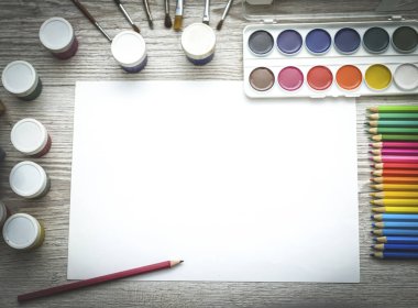 Çizim aletleri, kırtasiye malzemeleri, sanatçının çalışma yeri. Boya ve kalemler ve boş kağıtlar ahşap masa, üst görüş, düz döşeme, kopyalama alanı. okul çizim malzemeleri