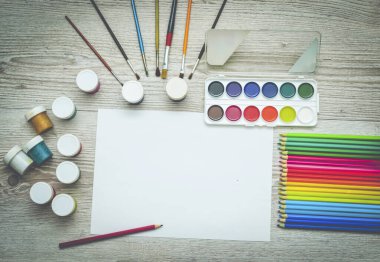 Çizim aletleri, kırtasiye malzemeleri, sanatçının çalışma yeri. Boya ve kalemler ve boş kağıtlar ahşap masa, üst görüş, düz döşeme, kopyalama alanı. okul çizim malzemeleri