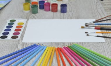 Çizim aletleri, kırtasiye malzemeleri, sanatçının çalışma yeri. Boya ve kalemler ve boş kağıtlar ahşap masa, üst görüş, düz döşeme, kopyalama alanı. okul çizim malzemeleri