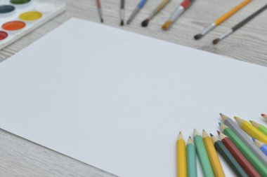 Çizim aletleri, kırtasiye malzemeleri, sanatçının çalışma yeri. Boya ve kalemler ve boş kağıtlar ahşap masa, üst görüş, düz döşeme, kopyalama alanı. okul çizim malzemeleri