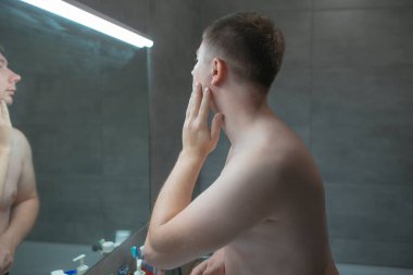 Adam tıraş olmadan önce aynaya bakıyor.