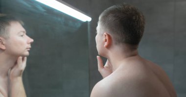 Adam tıraş olmadan önce aynaya bakıyor.