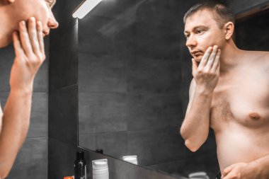 Adam tıraş olmadan önce aynaya bakıyor.