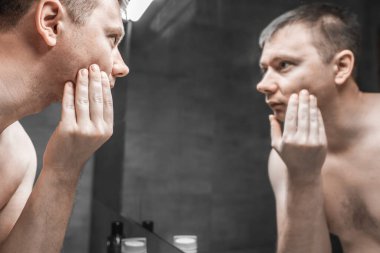 Adam tıraş olmadan önce aynaya bakıyor.