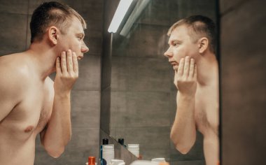 Adam tıraş olmadan önce aynaya bakıyor.