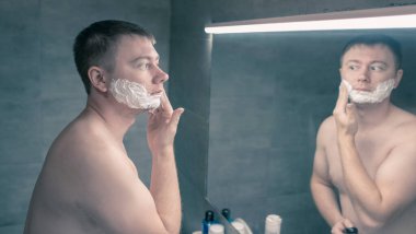 Adam yüzüne tıraş jeli sürüyor.