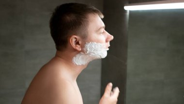 Adam yüzüne tıraş jeli sürüyor.