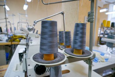 Üretim aşamasındaki bir dikiş makinesine yerleştirilmiş büyük dikiş makaraları