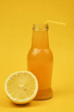 Sarı arka planda küçük bir turboçka ile bir şişe apleksin suyu bir limonun yanında duruyor.