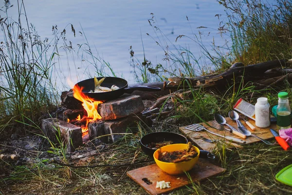 Tavadaki balık nehir kıyısında bir ateşte kızarır. Nehir kenarında akşam yemeği ve kazıkta yemek.