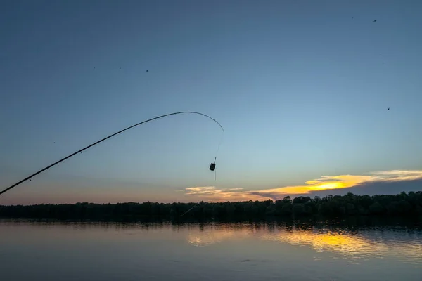 リールと釣り糸の釣り竿は日没時に川岸にあります — ストック写真