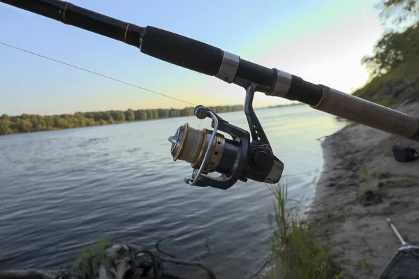 リールと釣り糸の釣り竿が川岸にあり — ストック写真