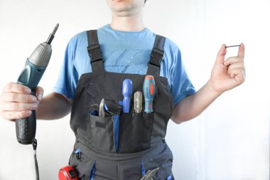 İşçi elinde bir tornavida ve elinde bir vida tutuyor.