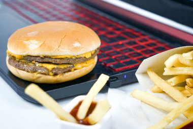 Fast food dizüstü bilgisayarın, patates kızartmasının ve hamburgerin yanında.