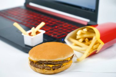 Fast food dizüstü bilgisayarın, patates kızartmasının ve hamburgerin yanında.