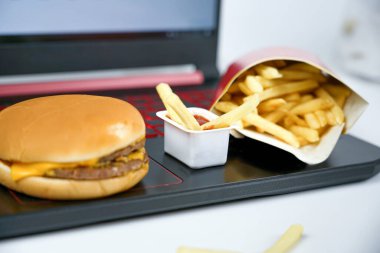 Fast food dizüstü bilgisayarın, patates kızartmasının ve hamburgerin yanında.