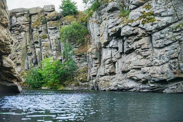 large stone rocks with a river between them with clear water. Trees grow on the rocks.