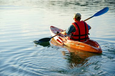 Suda kürek izleri, kayıktaki adam kürek çekiyor.