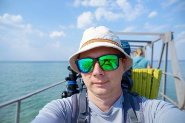 Sırt çantalı turist, rıhtımdaki kameraya selfie çekiyor.