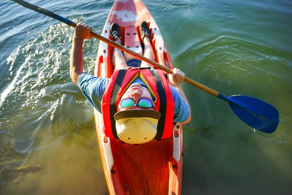 男は眼鏡と帽子で赤いカヌーに乗って泳ぐ トップ表示 — ストック写真