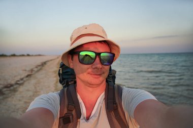 Sahildeki adam kameraya selfie çekiyor.