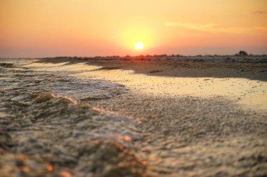 Deniz kenarında gün batımı. Güneş ışınları deniz köpüğüne yansıyor.
