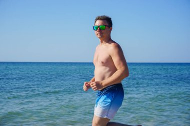 Adam sabahları deniz kıyısında masmavi suyla koşuyor..