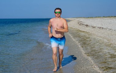 Adam sabahları deniz kıyısında masmavi suyla koşuyor..