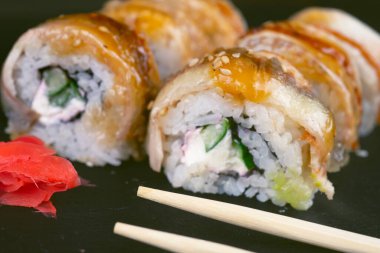 Yılanbalıklı suşi ve saman Wakamei salatası taş levhadan yapılmış siyah bir tahtada yatıyor.