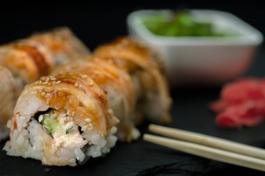 Yılanbalıklı suşi ve saman Wakamei salatası taş levhadan yapılmış siyah bir tahtada yatıyor.