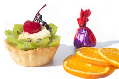 Kivili ve kremalı pasta, turuncu dilimlerin yanında. Beyaz arkaplan,