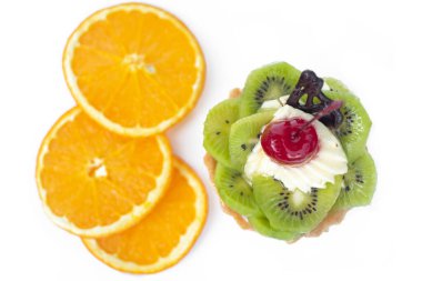 Kivili ve kremalı pasta, turuncu dilimlerin yanında. Beyaz arkaplan,