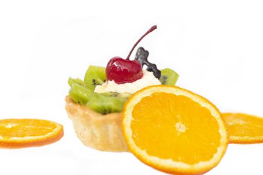 Kivili ve kremalı pasta, turuncu dilimlerin yanında. Beyaz arkaplan,