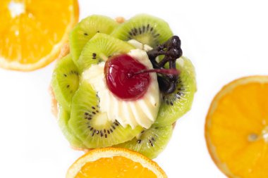 Kivili ve kremalı pasta, turuncu dilimlerin yanında. Beyaz arkaplan,